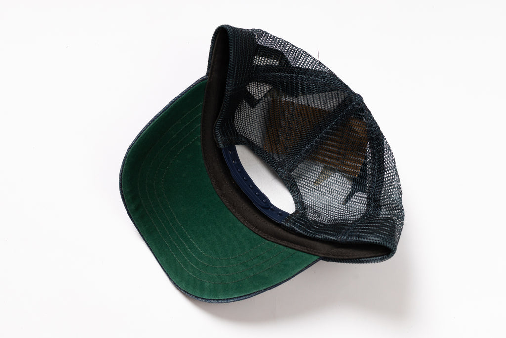 A green and black trucker cap with a dark green visor and black mesh back panels, shown from an overhead angle on a white background.