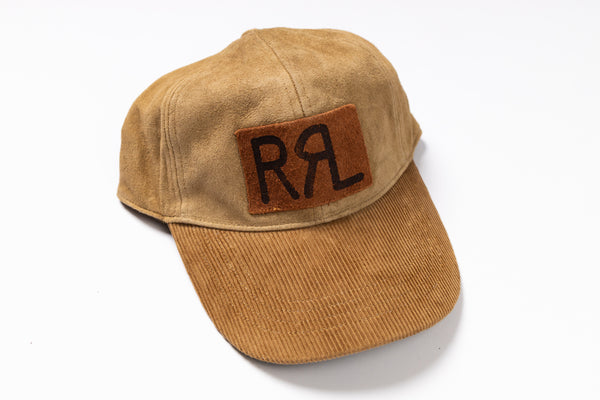 A tan corduroy baseball cap with a brown suede patch on the front featuring the black embroidered initials 'RRL', photographed on a clean white background.