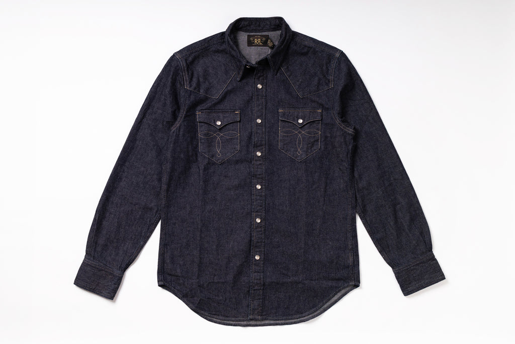 A dark indigo denim western-style shirt jacket with long sleeves, button-down front, and two chest pockets, laid flat on a white background.