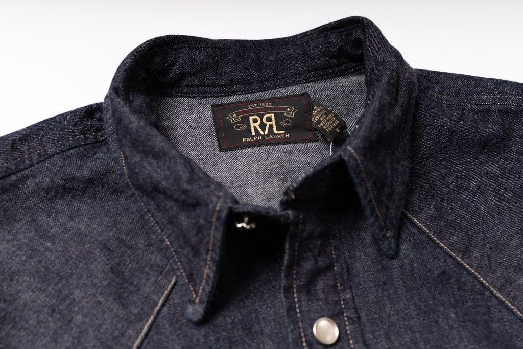 Close-up of a dark indigo denim button-down shirt collar with a visible neck label reading RRL Design.