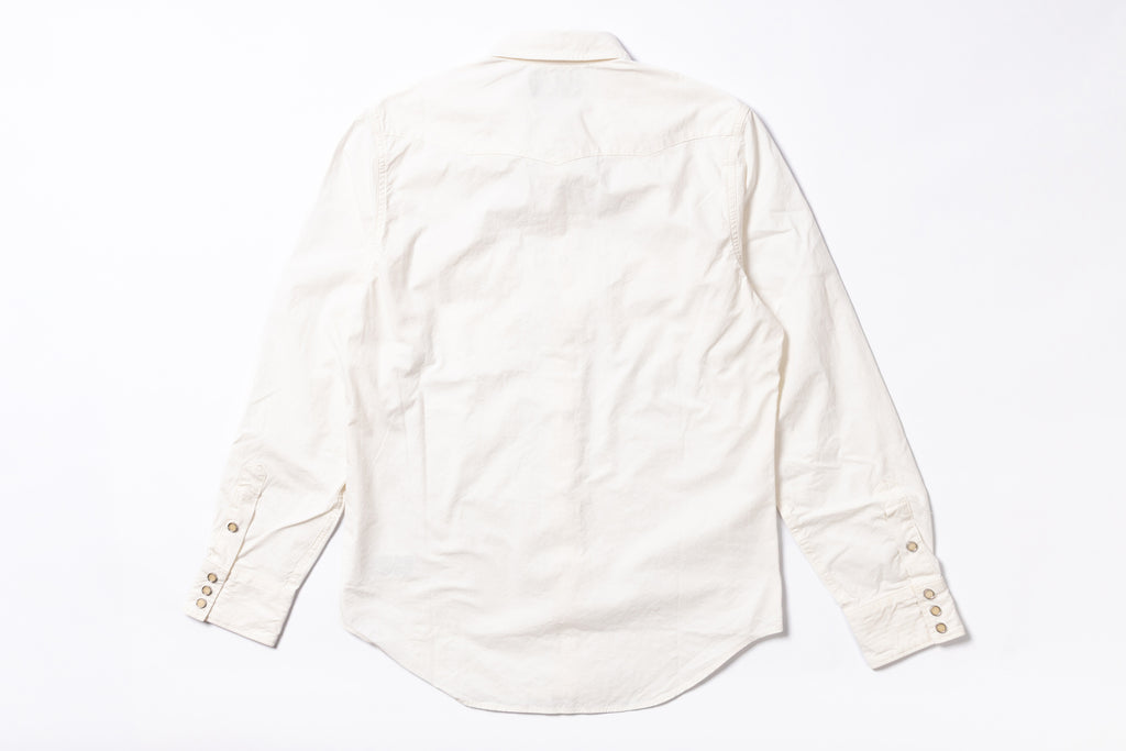 An off-white long-sleeve cotton  shirt shown from the back, laid flat on a white background. The shirt features a natural linen texture, a curved hem, and button details on the cuffs.