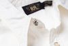 Close-up of a white button-up shirt collar with a metallic silver scalloped button and a black neck label reading RRL