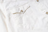 Close-up of a white button-up shirt featuring a chest pocket with a flap and decorative stitching, secured by a silver snap button.