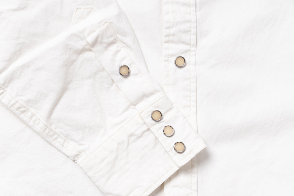 Close-up of a white button-up shirt sleeve with snap-button cuff and a vertical button placket.