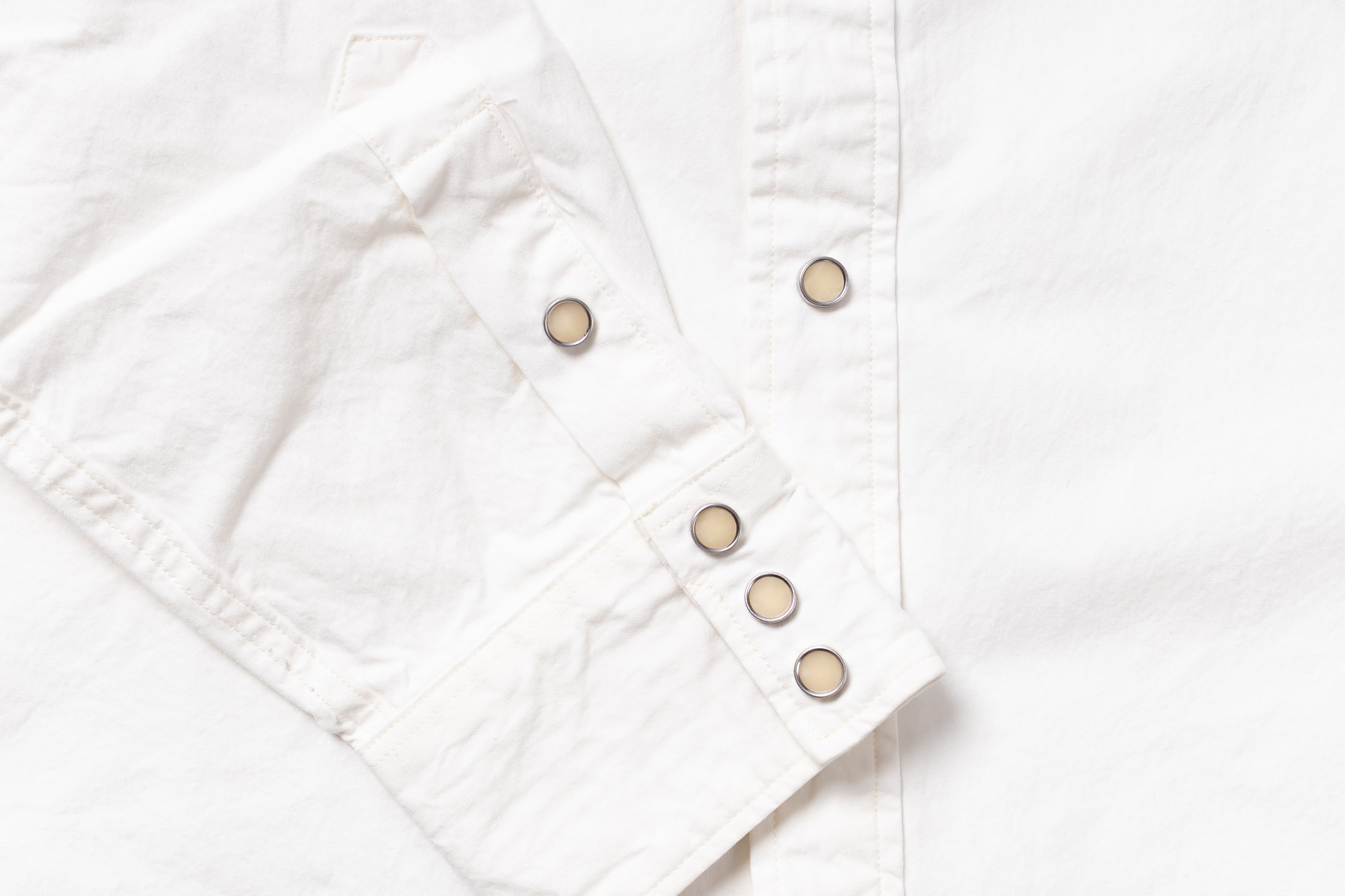 Close-up of a white button-up shirt sleeve with snap-button cuff and a vertical button placket.