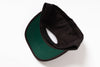 A folded baseball cap shown from the underside, featuring a dark green visor with black piping and a black crown, photographed on a clean white background.