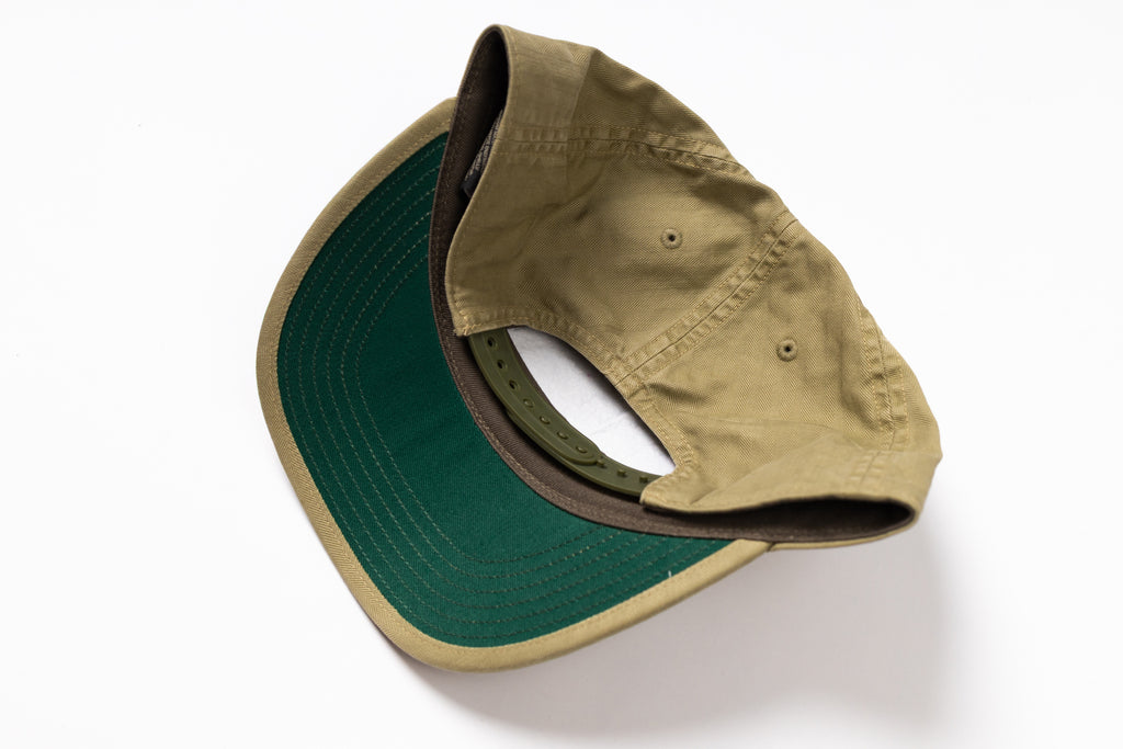 A two-tone baseball cap shown from an overhead angle, featuring a tan/khaki crown and a dark green visor with a tan edge.