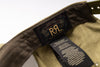 Close-up of the inside collar of a Ralph Lauren garment, showing the black neck label with gold 'RL' logo and a hanging care tag on olive green fabric.