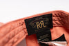 Close-up of a Ralph Lauren garment label stitched inside the collar, showing a black woven patch with gold embroidered 'RL' and 'Ralph Lauren' text on peach-colored fabric.
