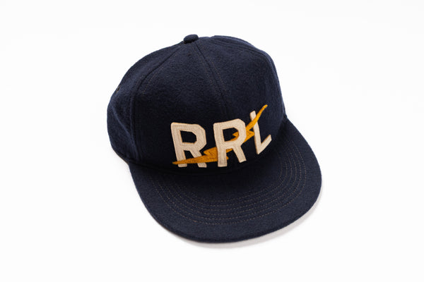 A dark navy blue baseball cap with 'RRL' embroidered on the front in beige and yellow, set against a plain white background.