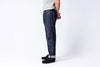 Person wearing dark blue jeans and black shoes on a white background