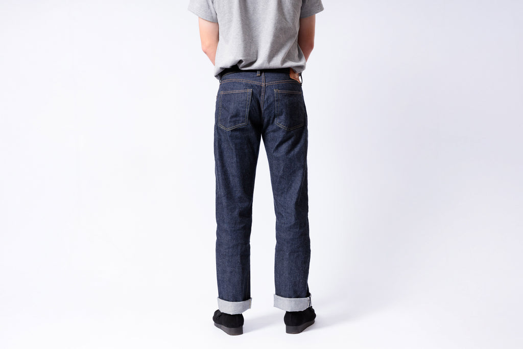 Person wearing blue jeans and a gray shirt on a white background