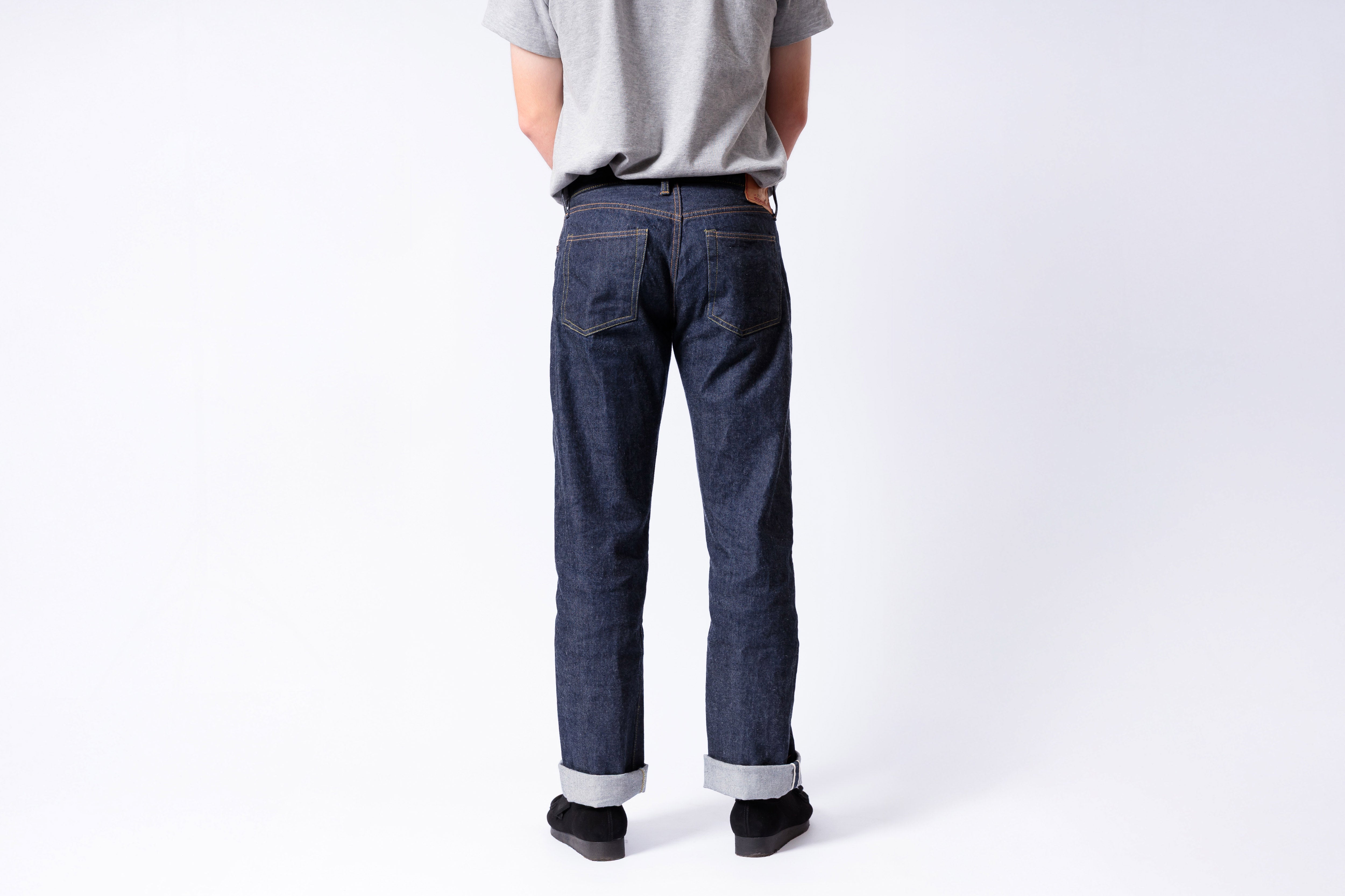 Person wearing blue jeans and a gray shirt on a white background