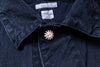 Close-up of a navy blue shirt with a decorative button on a dark background
