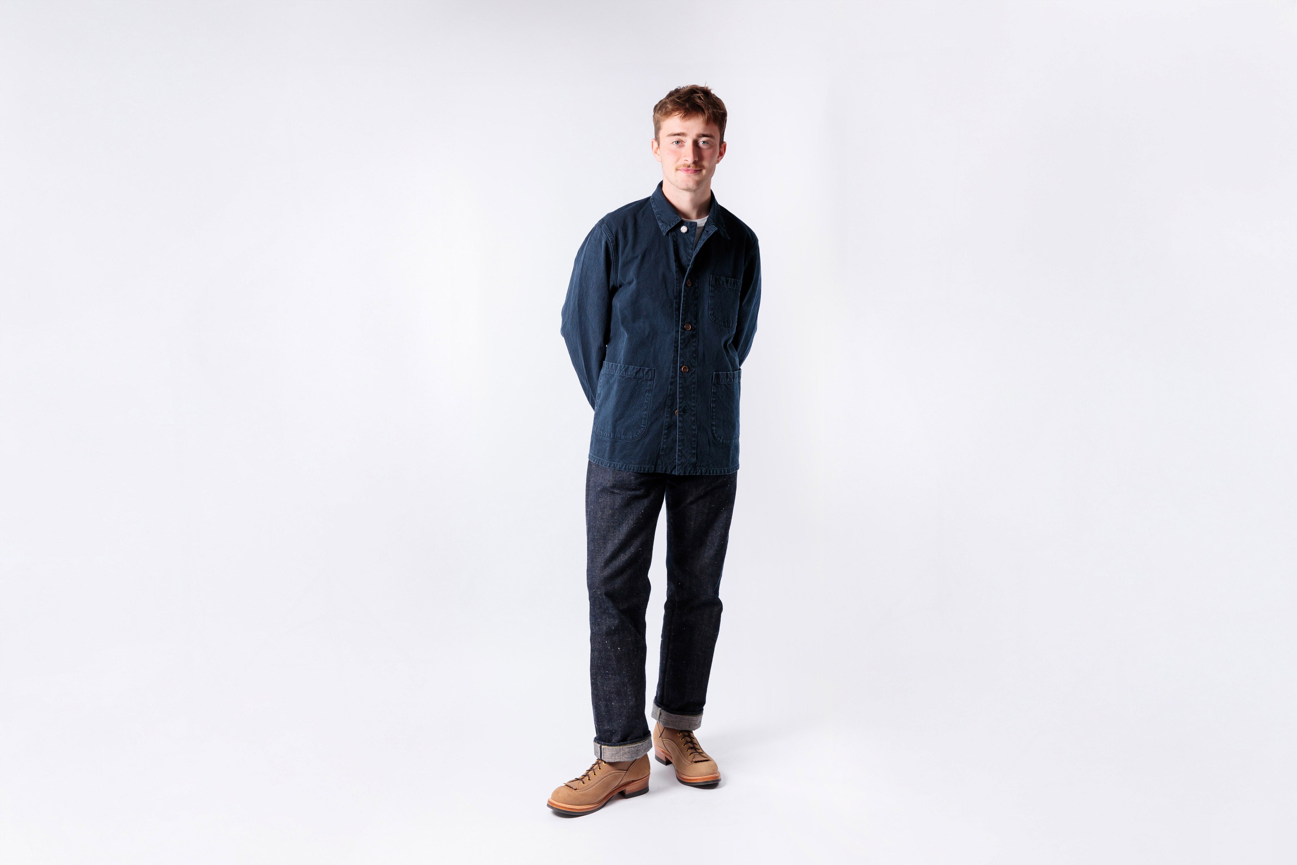 Person wearing a blue jumpsuit standing against a white background