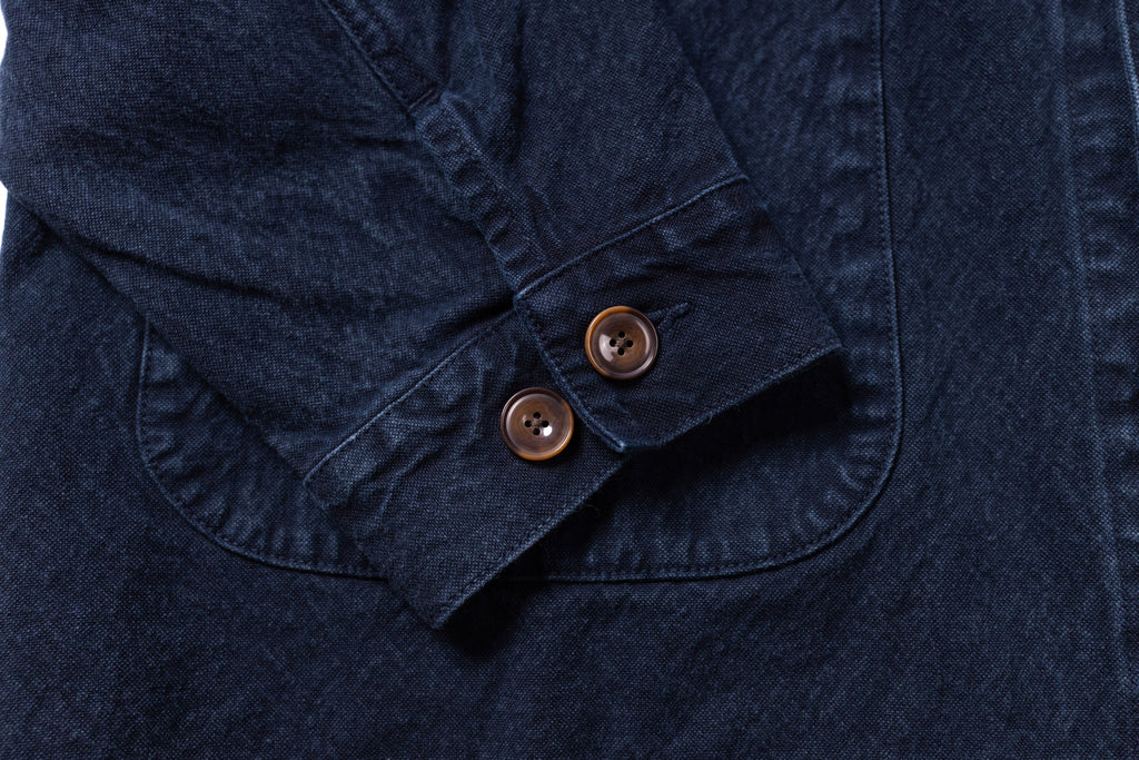 Close-up of a navy blue jacket with two buttons on a matching fabric background