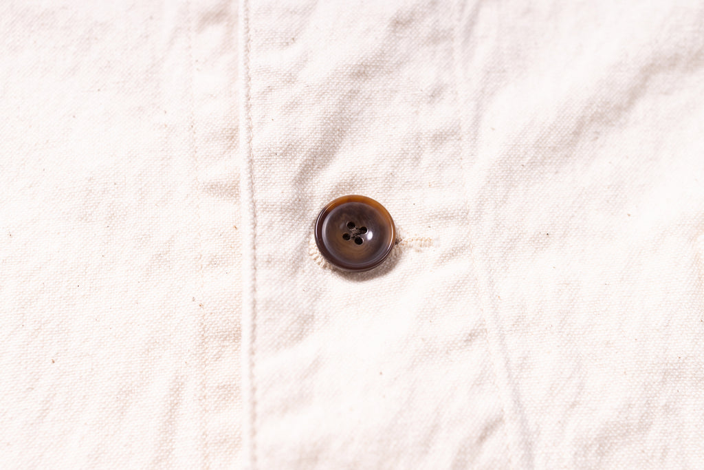 Close-up of a brown button on a beige fabric background
