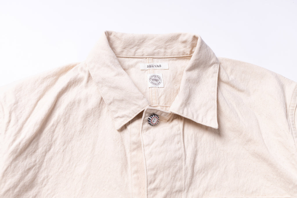 Beige shirt with a brand label on a light gray background