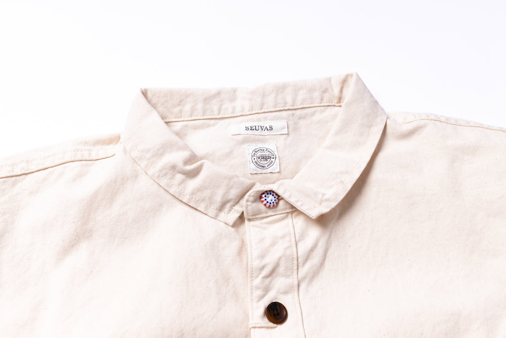 Close-up of a light-colored shirt with a brand label on a white background