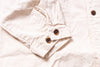 Close-up of a beige jacket with brown buttons on a light background