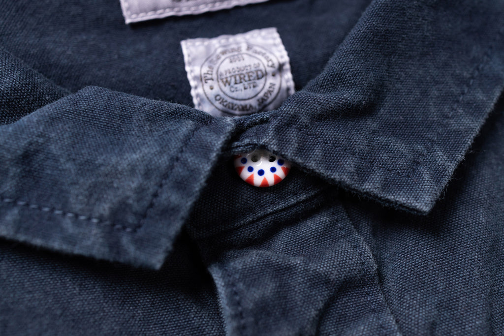 Close-up of a navy blue shirt with a brand label and button detail.