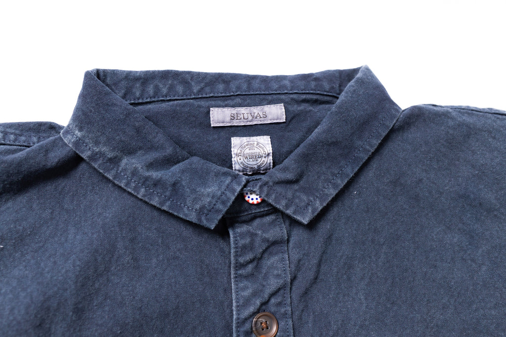 Close-up of a blue shirt collar with a brand label on a white background