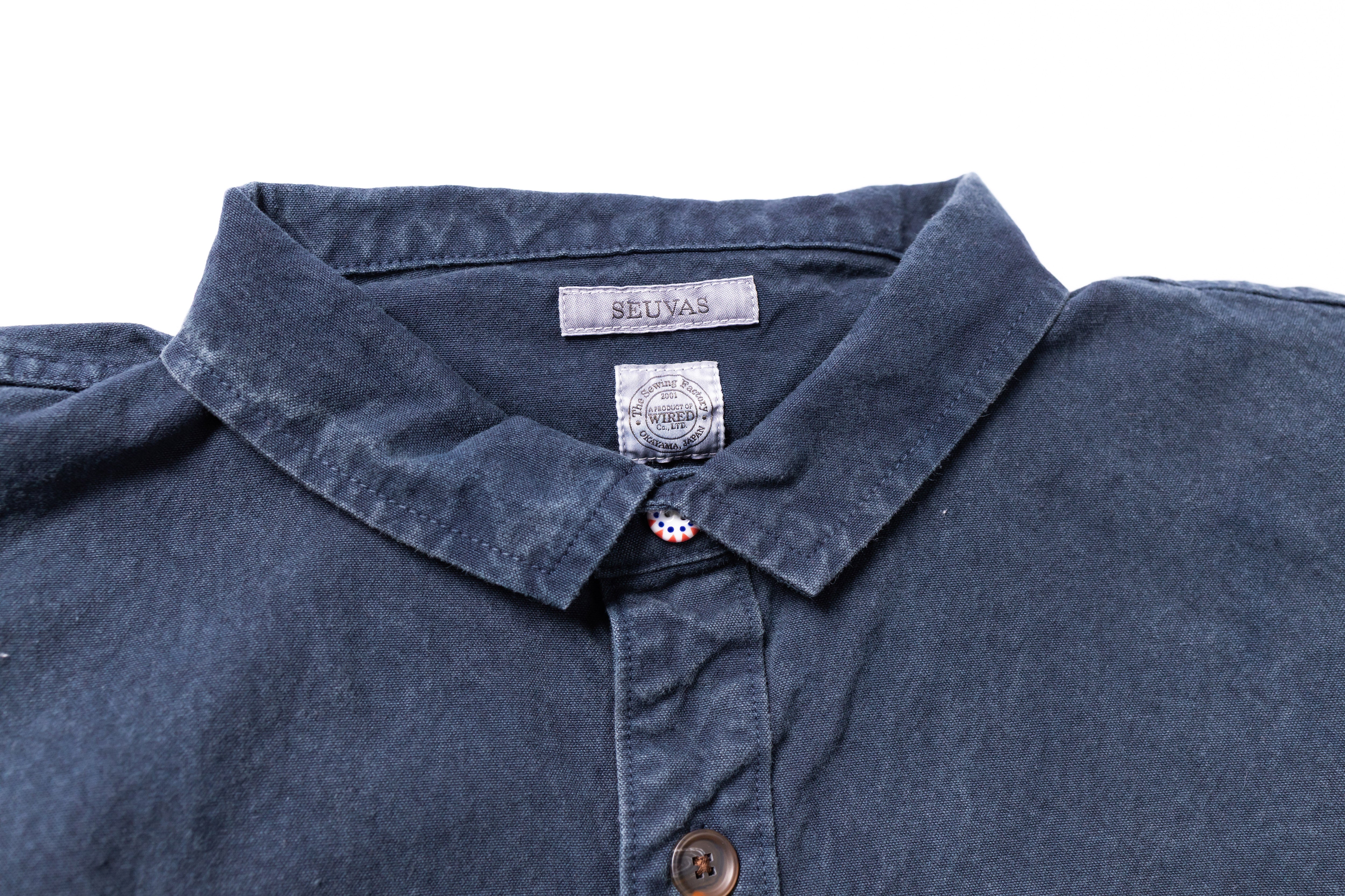 Close-up of a blue shirt collar with a brand label on a white background