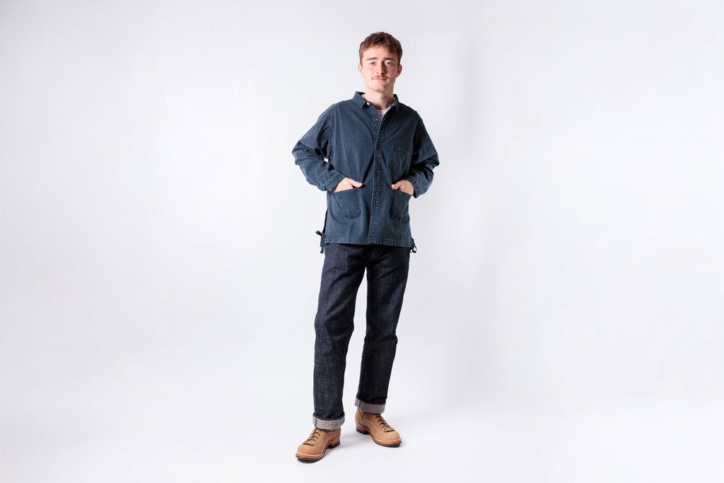 Man wearing a blue jacket and dark pants on a white background