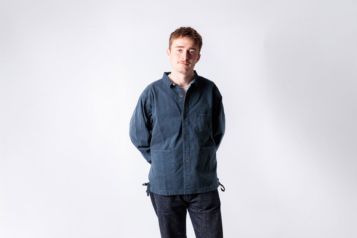 Man wearing a blue jacket and dark pants against a white background