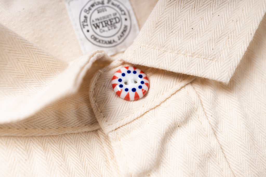 Close-up of a button on a beige fabric with a brand label in the background.