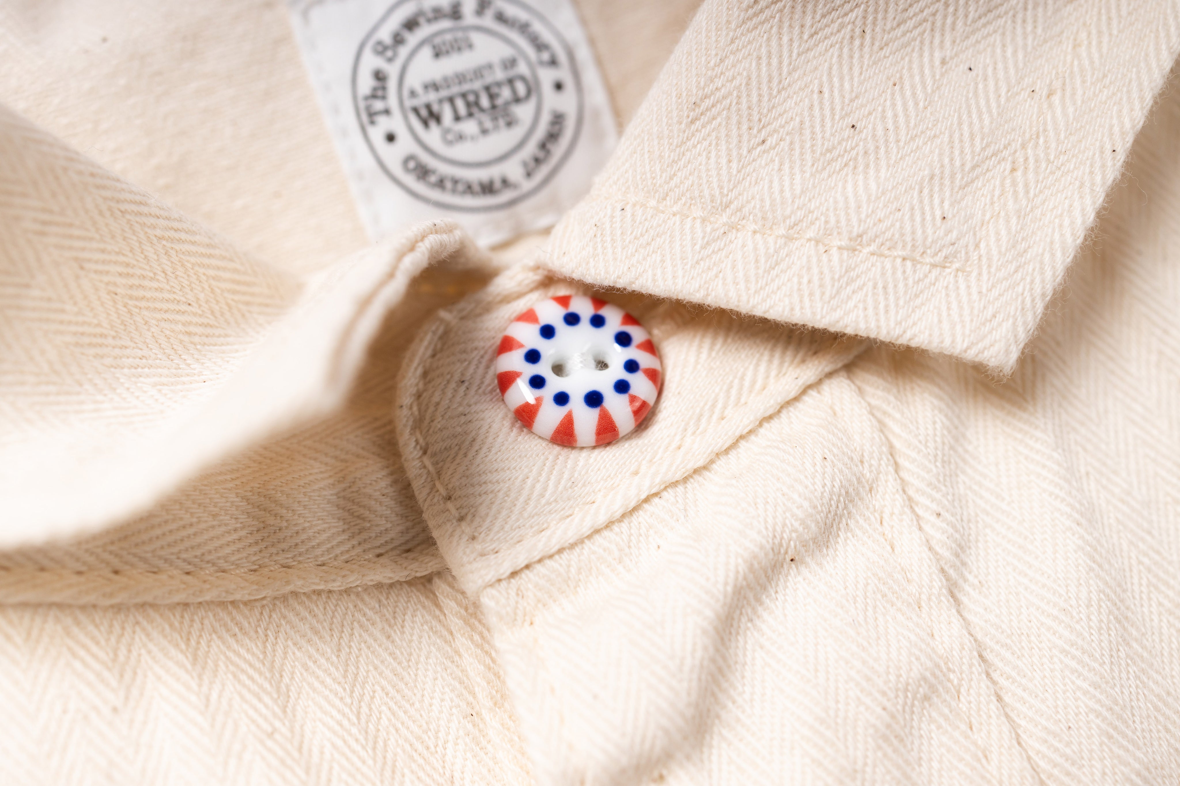 Close-up of a button on a beige fabric with a brand label in the background.