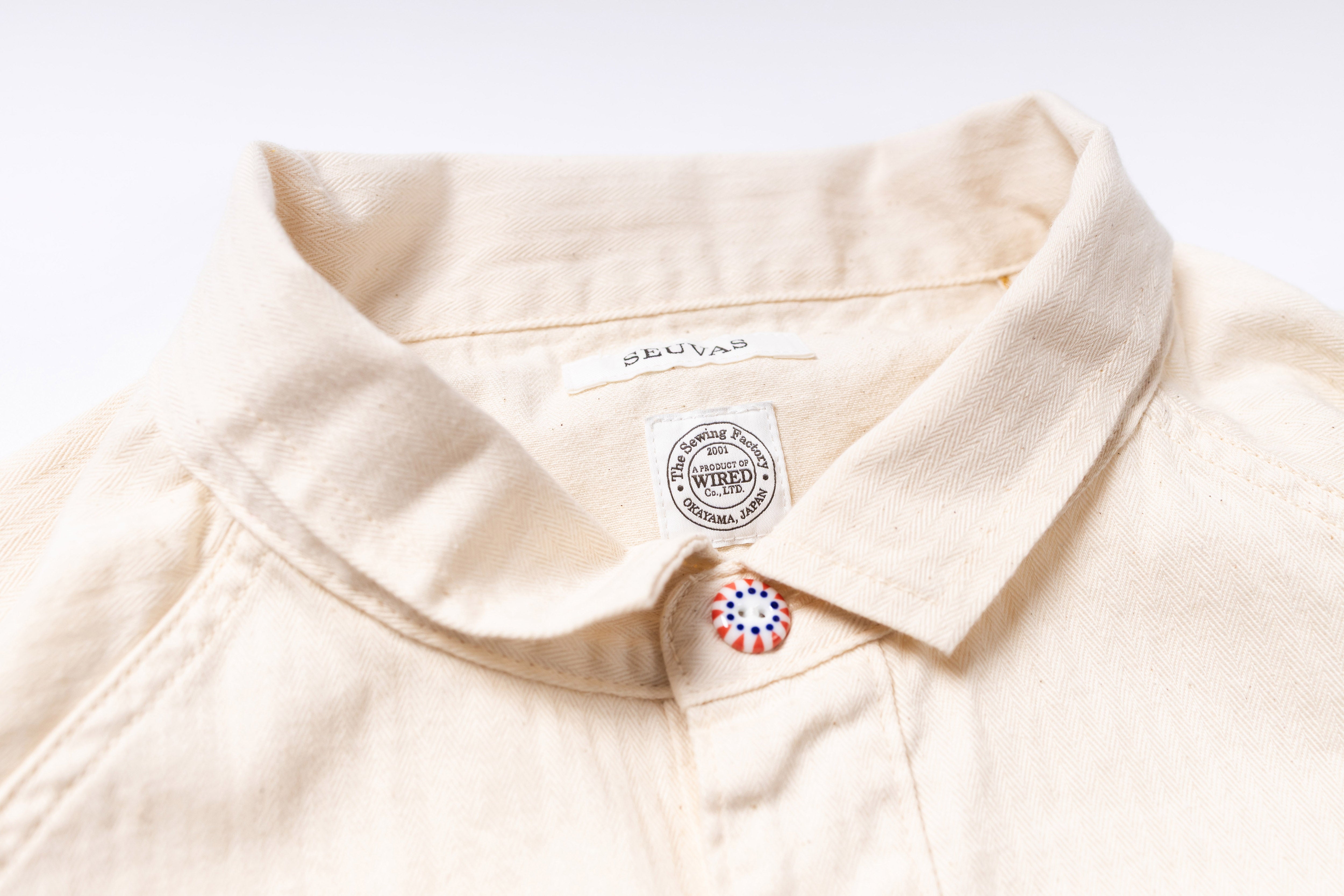 Close-up of a beige shirt with a brand label on a white background