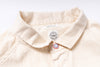 Close-up of a beige shirt with a brand label on a white background