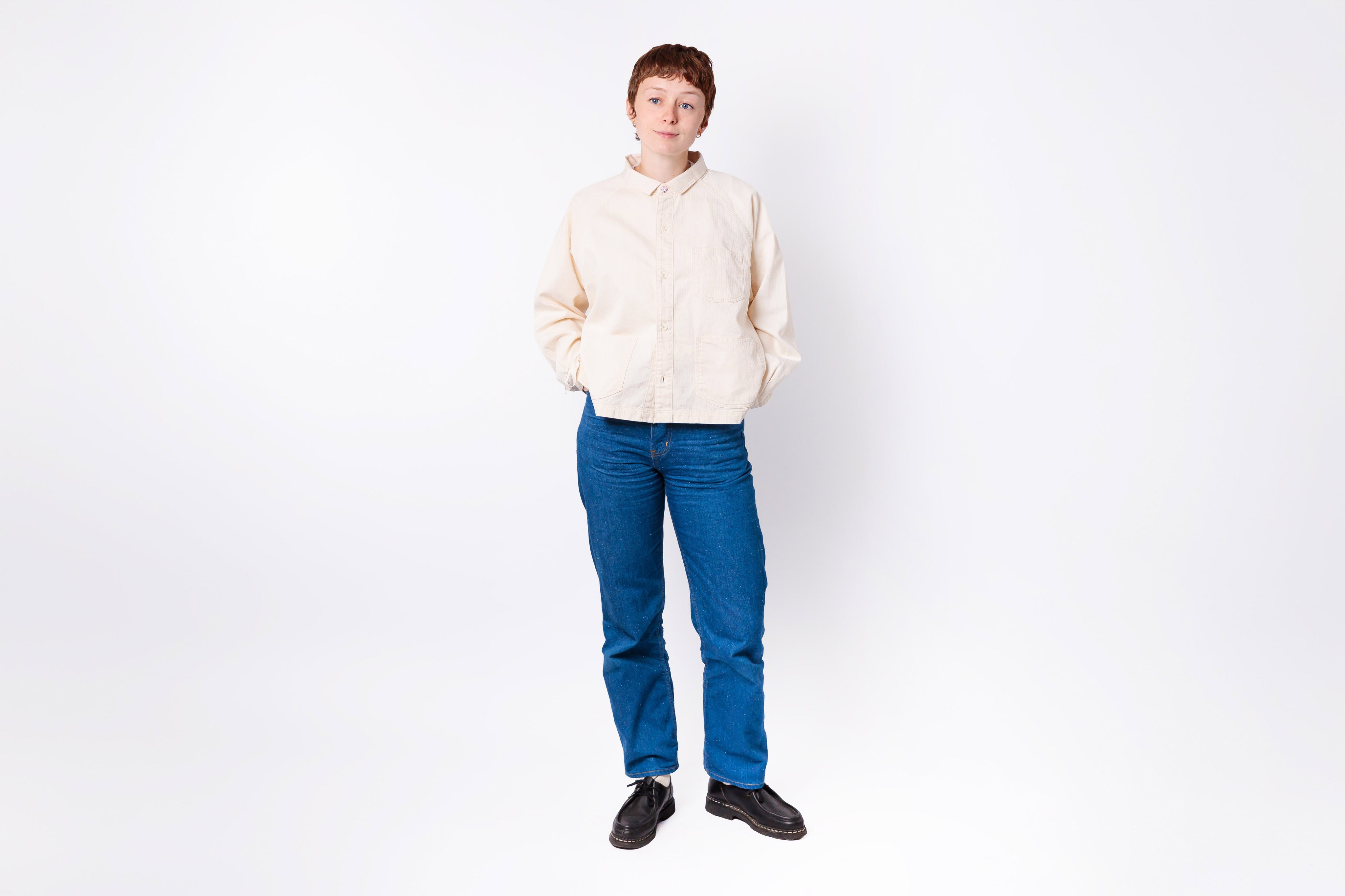 Person wearing a cream sweater and blue jeans on a white background