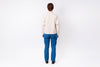 Person wearing a cream shirt and blue pants on a white background
