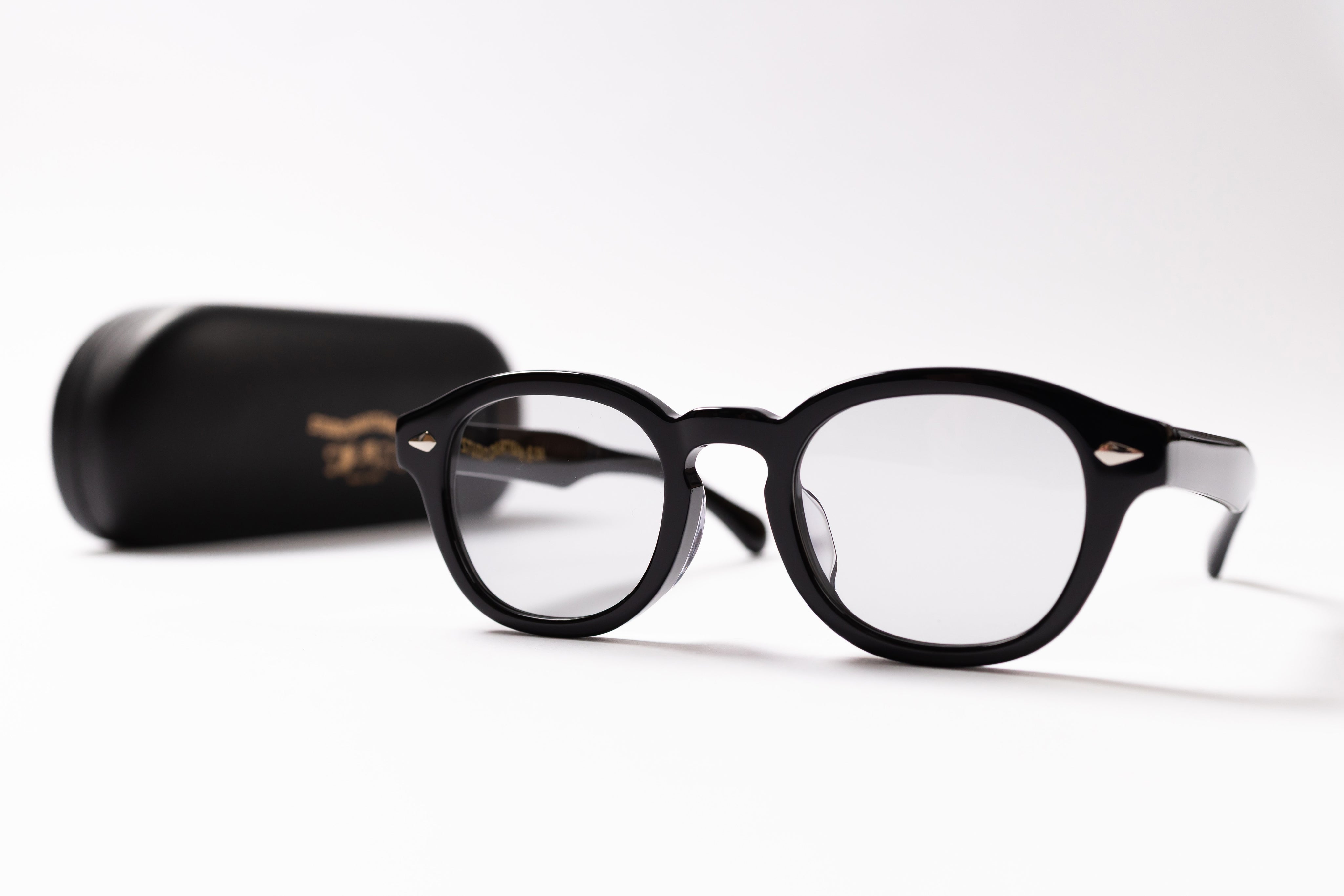 Black eyeglasses on a white background with a black case.