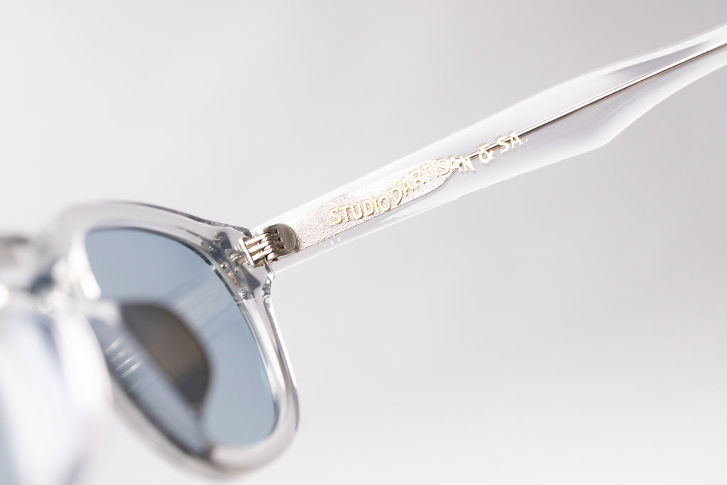 Sunglasses with a clear frame and reflective lenses on a light gray background