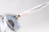 Sunglasses with a clear frame and reflective lenses on a light gray background