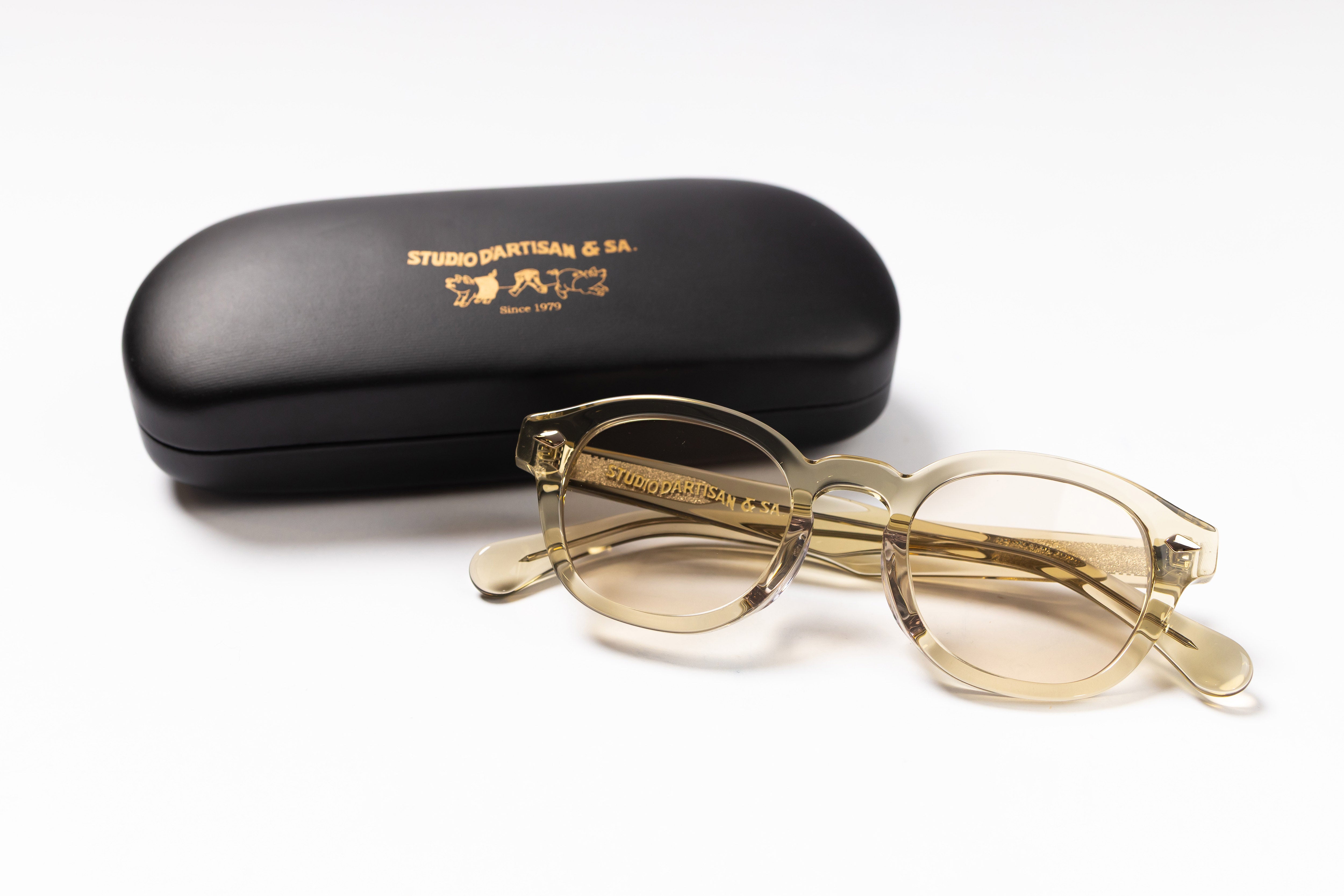 Pair of gold-rimmed glasses with a black case on a white background