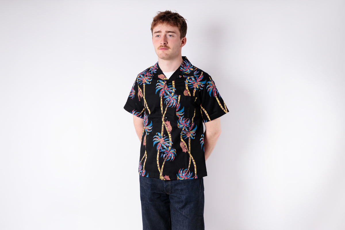 Man wearing a black patterned shirt against a white background