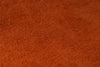 A close-up texture shot of a rust-orange woven fabric, showing the detailed knit pattern and color.