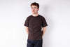 Man wearing a brown t-shirt and dark jeans against a white background