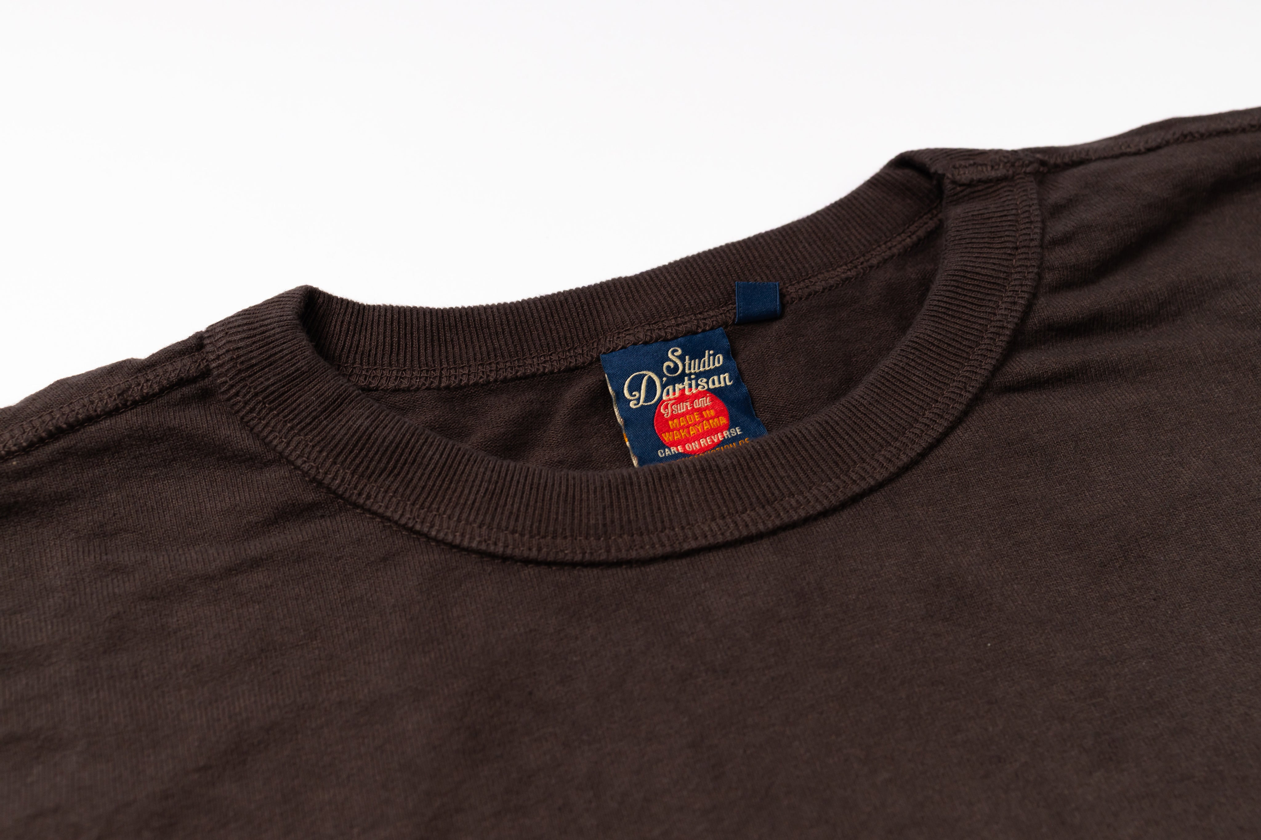 Brown t-shirt with a visible brand label on a white background