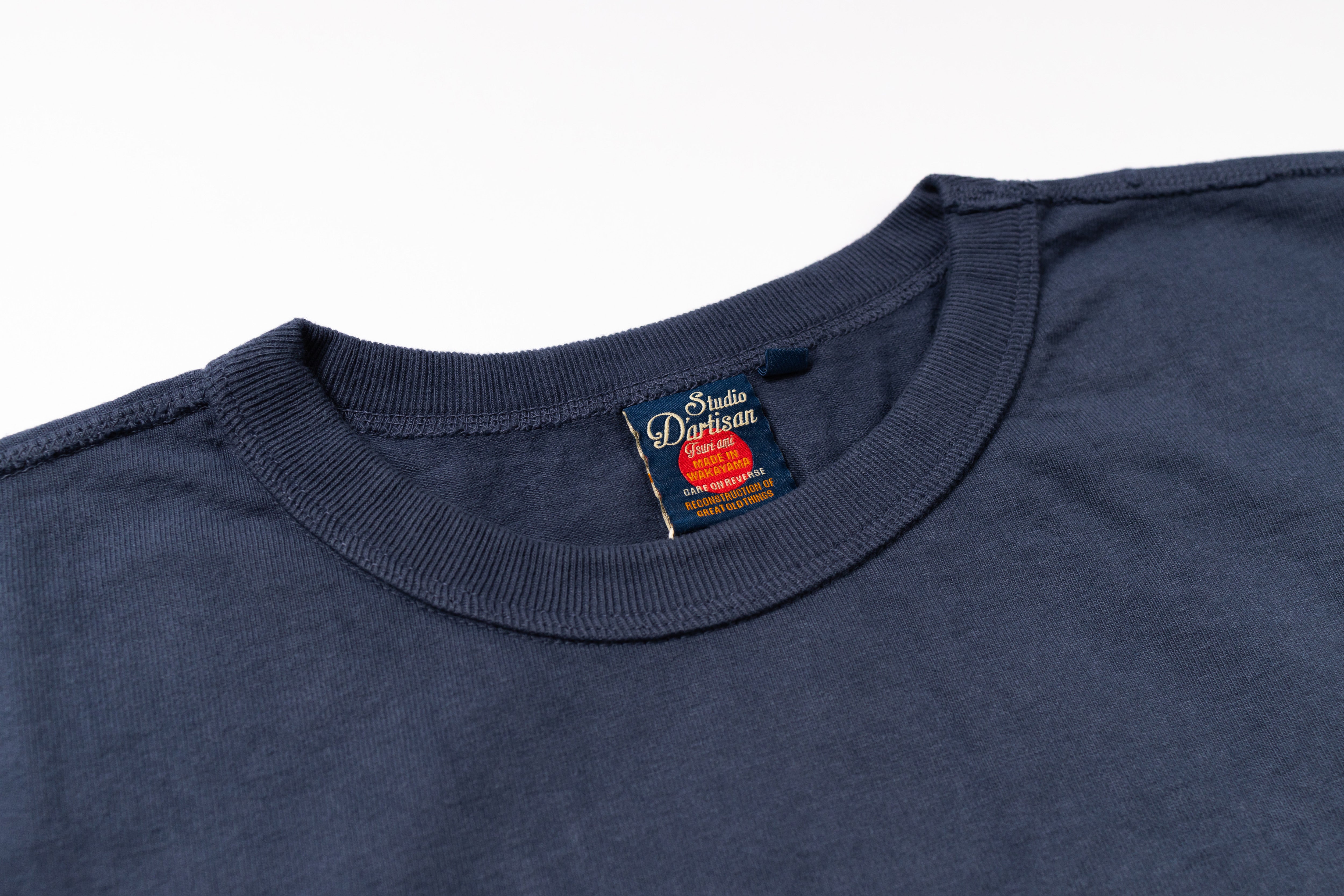 Close-up of a navy blue t-shirt with a brand label on a white background