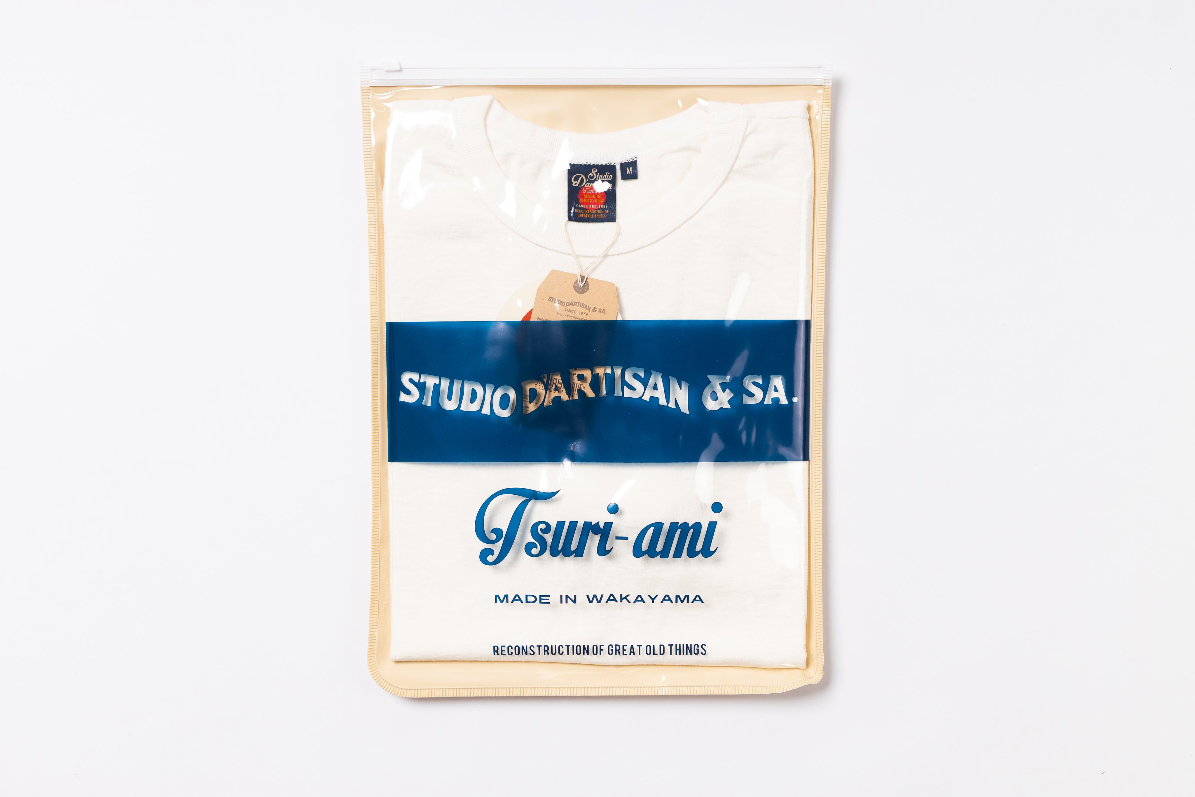Packaged t-shirt with 'Studio Artisan & Co' branding on a white background