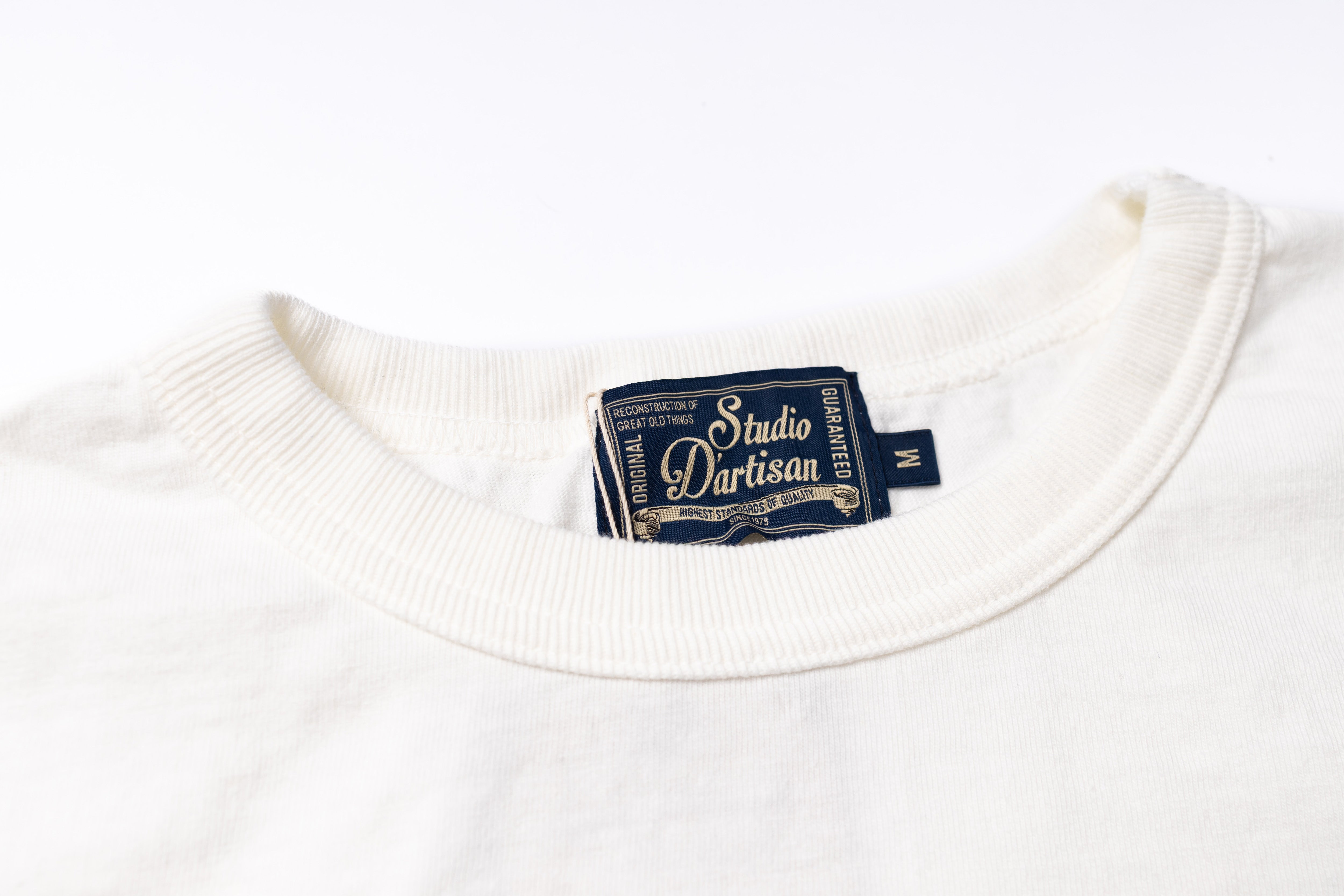 Close-up of a white crewneck t-shirt showing the inner neck label which reads 'Studio Partisan'