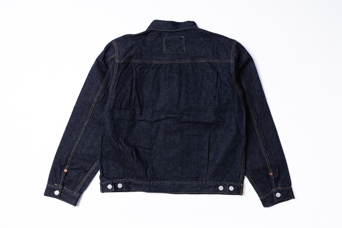 A dark indigo denim jacket shown from the back, laid flat against a clean white background.