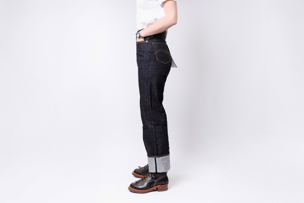 Person wearing dark jeans and brown shoes on a white background