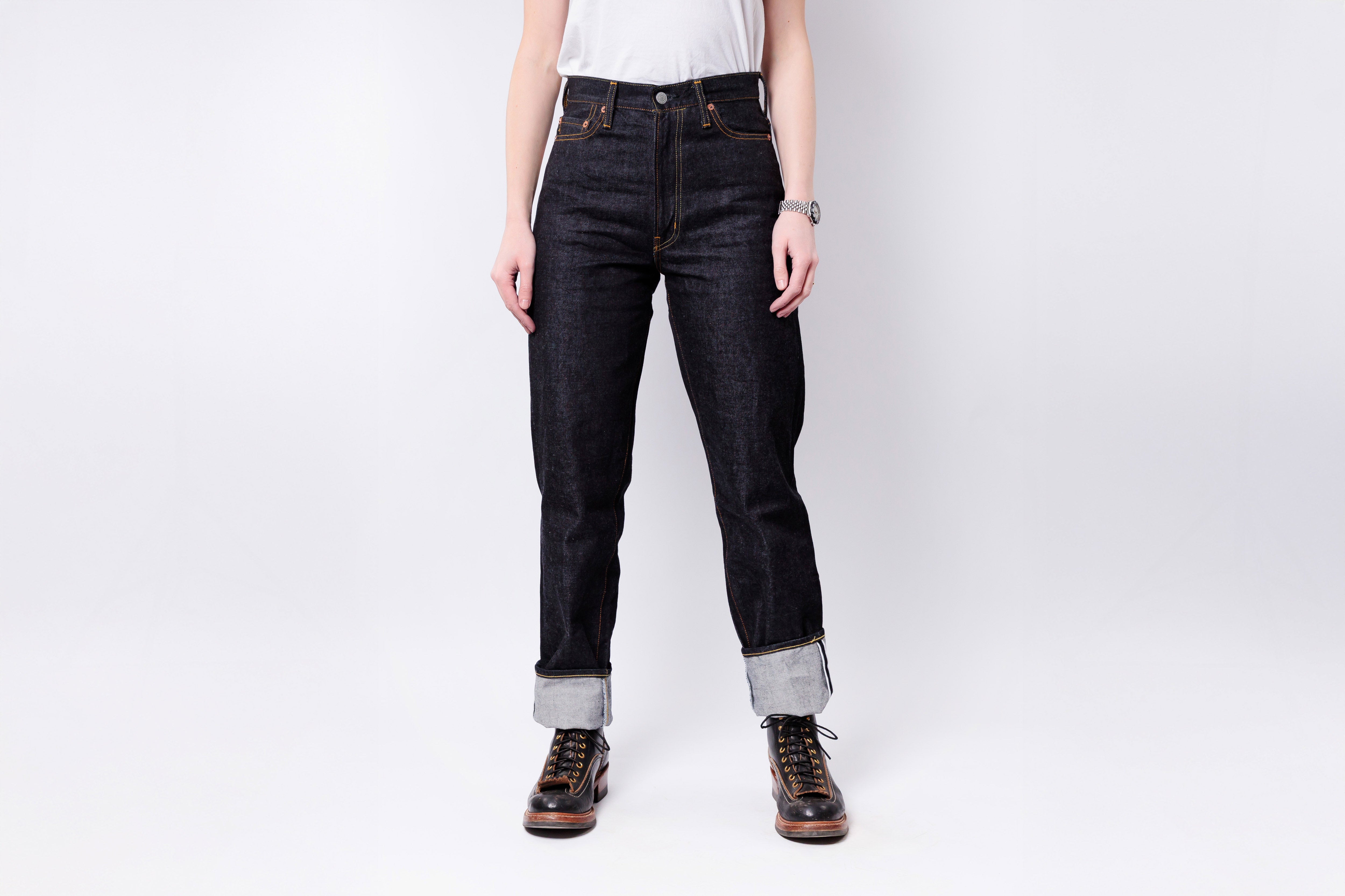 Person wearing dark jeans and boots on a white background