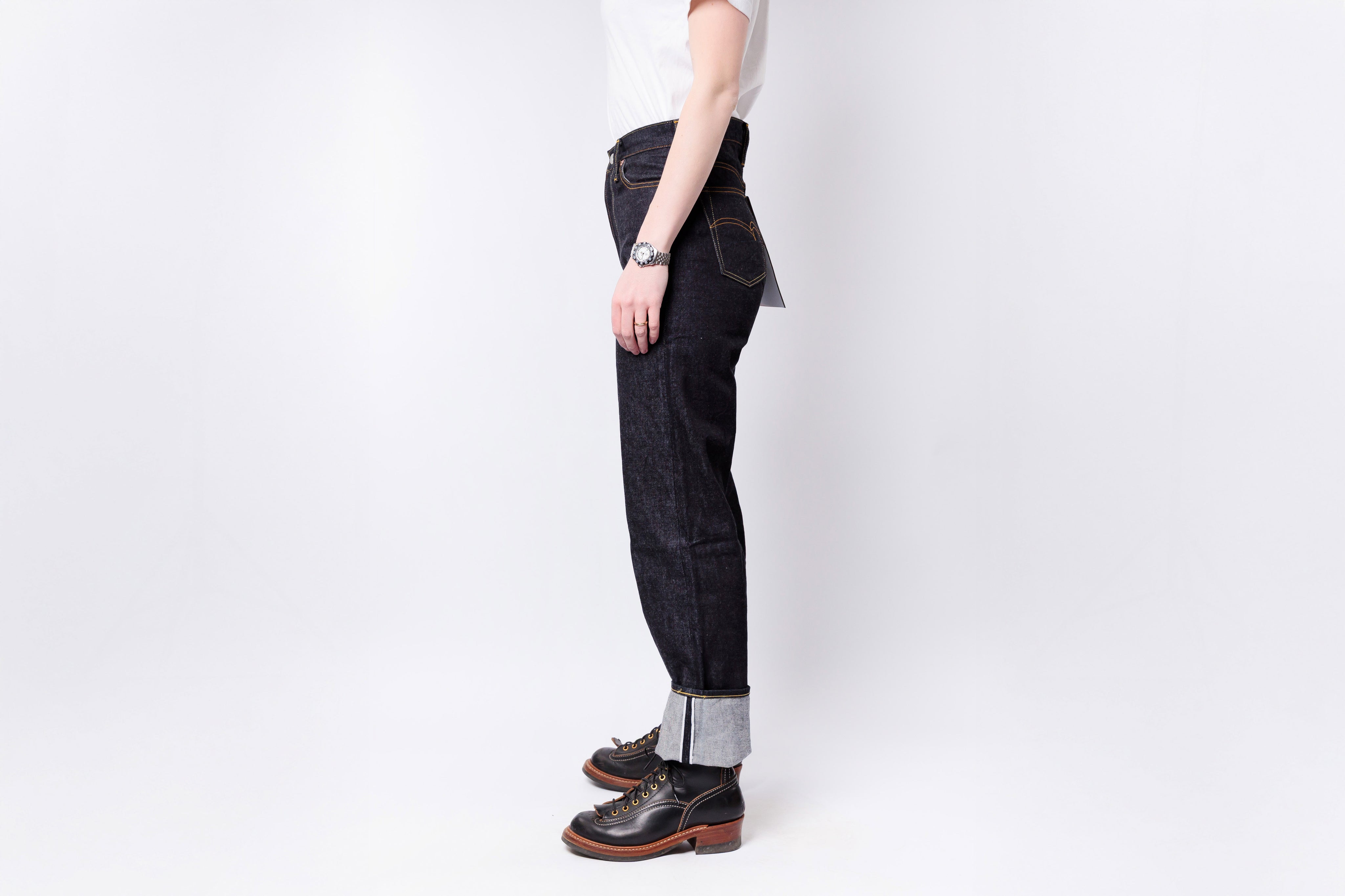 Person wearing dark jeans and brown shoes on a white background